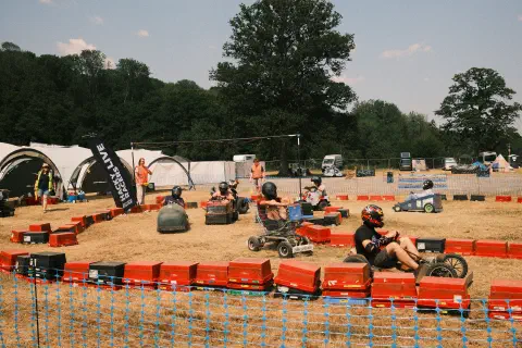 A makeshift racetrack made out of upturned crates around the racetrack several custom built vehicles race each other in the dusty ground