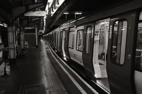 A black ad white photo taken on Edgeware Road station, the sign indicates this is platform 3, a train in the platform stands empty, it's doors open
