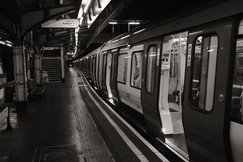 A black ad white photo taken on Edgeware Road station, the sign indicates this is platform 3, a train in the platform stands empty, it's doors open